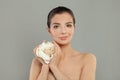 Young brunette woman holding white rose flower in her hands on grey background Royalty Free Stock Photo