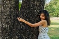 Young brunette woman hugging the big tree in the park. Beautiful girl embracing wood tree with love of nature and Royalty Free Stock Photo