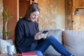 Young brunette woman laughing chatting with the mobile phone sitting on the sofa at home Royalty Free Stock Photo