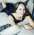 Young brunette woman in loft laying on bed smiling Royalty Free Stock Photo