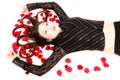 Young woman lying on floor with rose petals in her hair Royalty Free Stock Photo