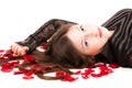 Young woman lying on floor with rose petals in her hair Royalty Free Stock Photo