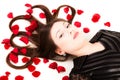 Young woman lying on floor with rose petals in her hair Royalty Free Stock Photo