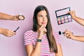 Young brunette woman with make up cosmetic around thinking concentrated about doubt with finger on chin and looking up wondering