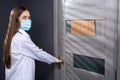 Young brunette woman in a medical mask opening the door of a store just reopened after quarantine. Protection against viruses and