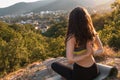 Young brunette woman meditating in the Park. The concept of yoga, sports and meditation. Mountain view and settlement in the