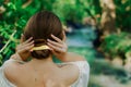 Young brunette woman with naked shoulders and elegant twist hairstyle with gold hairpin touches her hair with two hands side back Royalty Free Stock Photo