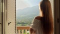 Young brunette woman opens window blinds at her villa and walking out on the terrace or balcony. Concept of summertime Royalty Free Stock Photo