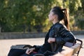 Young brunette woman outdoors portrait. Resting on bench in the park. Side view Royalty Free Stock Photo