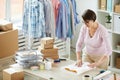 Young brunette woman packing folded casualwear into paper Royalty Free Stock Photo