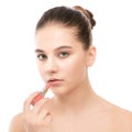 Young brunette woman with perfect clean face applying lipstick. Isolated on a white. Royalty Free Stock Photo