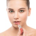 Young brunette woman with perfect clean face applying lipstick. Isolated on a white. Royalty Free Stock Photo