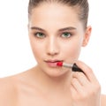 Young brunette woman with perfect clean face applying lipstick. Isolated on a white. Royalty Free Stock Photo