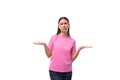 young brunette woman in a pink basic t-shirt shrugging her shoulders on a white background with copy space Royalty Free Stock Photo