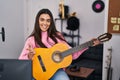 Young brunette woman playing classic guitar at music studio celebrating achievement with happy smile and winner expression with Royalty Free Stock Photo