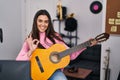 Young brunette woman playing classic guitar at music studio doing ok sign with fingers, smiling friendly gesturing excellent Royalty Free Stock Photo