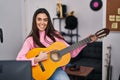 Young brunette woman playing classic guitar at music studio smiling happy pointing with hand and finger Royalty Free Stock Photo