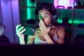 Young brunette woman playing video games with smartphone covering mouth with hand, shocked and afraid for mistake Royalty Free Stock Photo