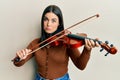 Young brunette woman playing violin depressed and worry for distress, crying angry and afraid Royalty Free Stock Photo