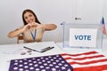 Young brunette woman at political election sitting by ballot smiling in love showing heart symbol and shape with hands