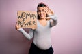 Young brunette woman pregnant expecting baby holding banner asking for women power with open hand doing stop sign with serious and Royalty Free Stock Photo