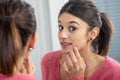Young brunette woman puting makeup in the mirror