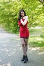 young brunette woman in a red dress standing on alley in city park in summer Royalty Free Stock Photo