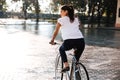 Young brunette woman riding on bicycle in city street Royalty Free Stock Photo