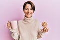 Young brunette woman with short hair drinking a cup of coffee and cookie smiling with a happy and cool smile on face Royalty Free Stock Photo
