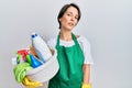 Young brunette woman with short hair wearing apron holding cleaning products looking sleepy and tired, exhausted for fatigue and Royalty Free Stock Photo