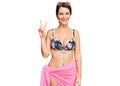 Young brunette woman with short hair wearing bikini smiling with happy face winking at the camera doing victory sign Royalty Free Stock Photo