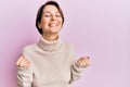 Young brunette woman with short hair wearing casual winter sweater excited for success with arms raised and eyes closed Royalty Free Stock Photo