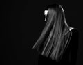 Young brunette woman shows her luxurious healthy recovered long straight hair. Black and white