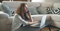 A young brunette woman sits in a room and is working on a laptop, typing text. The mobile phone rang, the woman answered