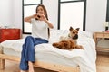 Young brunette woman sitting on the bed with two dogs smiling in love showing heart symbol and shape with hands Royalty Free Stock Photo