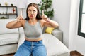 Young brunette woman sitting on the sofa at home pointing up looking sad and upset, indicating direction with fingers, unhappy and Royalty Free Stock Photo