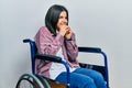 Young brunette woman sitting on wheelchair laughing nervous and excited with hands on chin looking to the side Royalty Free Stock Photo