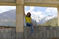 Young woman sitting on the window sill of a destroyed abandoned building in the mountains.