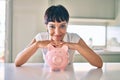 Young brunette woman smiling happy showing proud piggy bank with savings Royalty Free Stock Photo