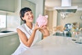 Young brunette woman smiling happy showing proud piggy bank with savings Royalty Free Stock Photo