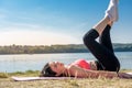 Young brunette woman in sportswear doing stretching her legs after the workout  on the lake near daytime. Healthy lifestyle Royalty Free Stock Photo