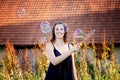 Young brunette woman standing outdoors and blowing soap bubbles Royalty Free Stock Photo