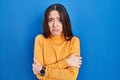 Young brunette woman standing over blue background shaking and freezing for winter cold with sad and shock expression on face Royalty Free Stock Photo