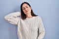 Young brunette woman standing over blue background suffering of neck ache injury, touching neck with hand, muscular pain Royalty Free Stock Photo