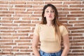 Young brunette woman standing over bricks wall making fish face with lips, crazy and comical gesture Royalty Free Stock Photo