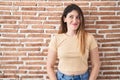 Young brunette woman standing over bricks wall smiling looking to the side and staring away thinking Royalty Free Stock Photo