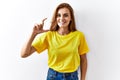 Young brunette woman standing over isolated background smiling and confident gesturing with hand doing small size sign with Royalty Free Stock Photo