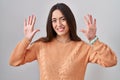 Young brunette woman standing over white background showing and pointing up with fingers number ten while smiling confident and Royalty Free Stock Photo