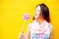 Young woman standing at yellow wall with pinwheel Royalty Free Stock Photo