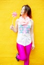 Young woman standing at yellow wall with pinwheel Royalty Free Stock Photo